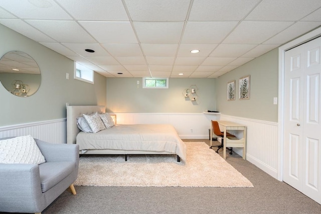 carpeted bedroom with a wainscoted wall, a paneled ceiling, and recessed lighting