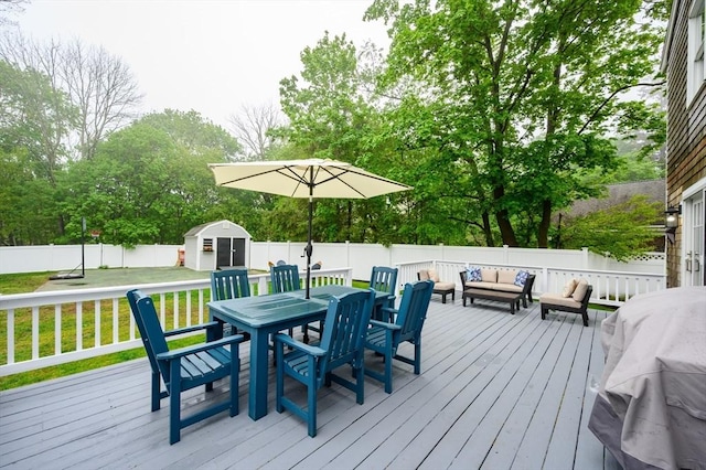 deck featuring an outdoor living space, outdoor dining space, a storage shed, and an outbuilding