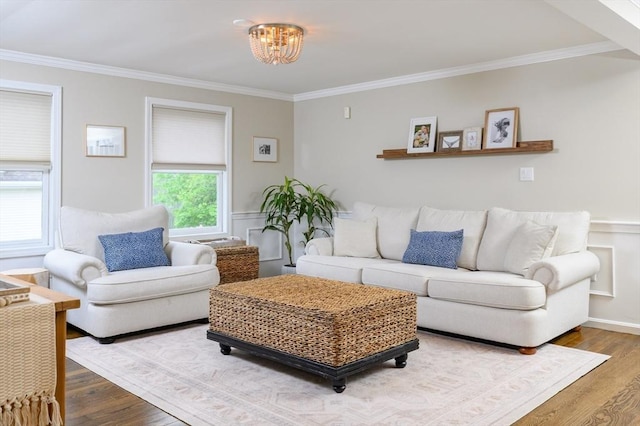 living area featuring wood finished floors, crown molding, a chandelier, and a wainscoted wall