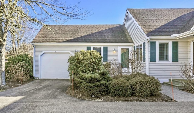 view of front of house with an attached garage, aphalt driveway, and roof with shingles