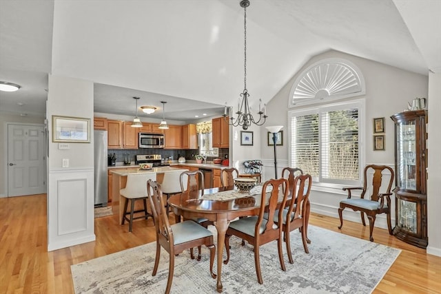 dining area featuring lofted ceiling, wainscoting, and light wood-style flooring