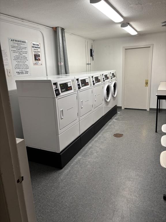 shared laundry room featuring washing machine and clothes dryer and a textured ceiling