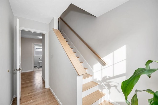 staircase featuring baseboards and wood finished floors