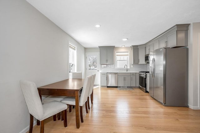 kitchen featuring light wood-style flooring, a sink, light countertops, appliances with stainless steel finishes, and gray cabinets