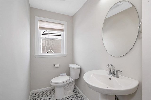 bathroom with a sink, toilet, and baseboards