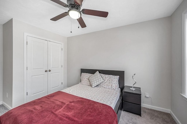 bedroom featuring light carpet, a ceiling fan, baseboards, and a closet