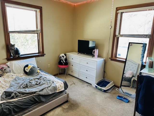 bedroom featuring light carpet, multiple windows, and baseboards