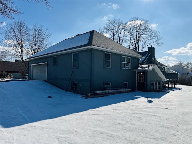 view of snowy exterior with an attached garage