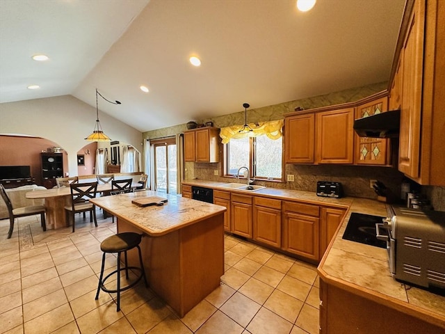 kitchen featuring under cabinet range hood, a kitchen island, light tile patterned floors, and a sink