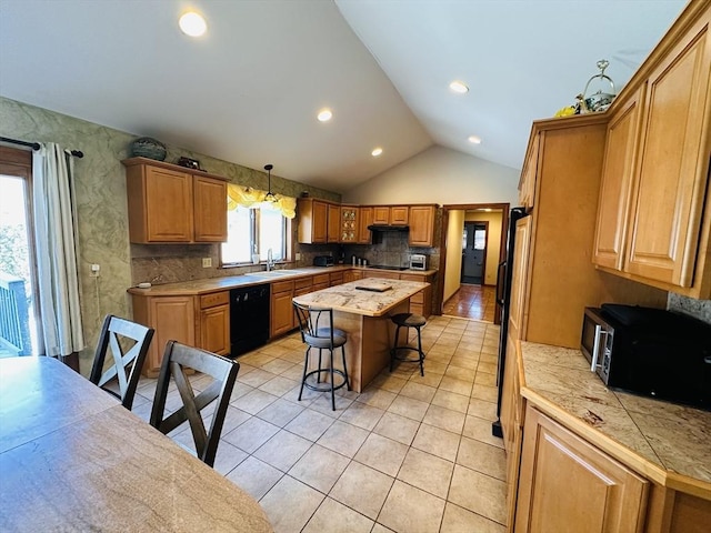 kitchen with decorative light fixtures, a breakfast bar area, a sink, a kitchen island, and black appliances