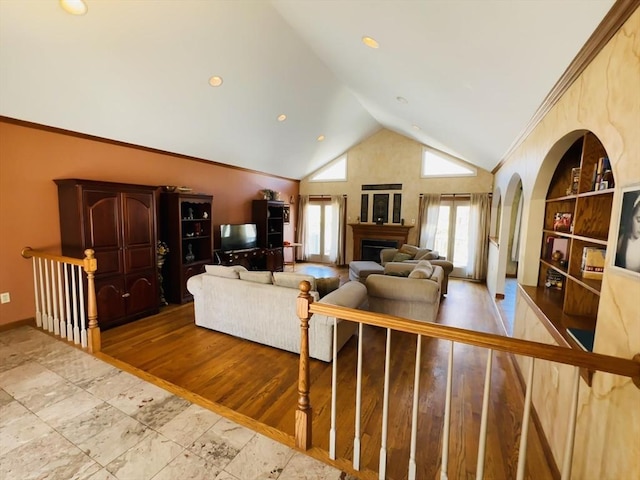 living room with light wood finished floors, baseboards, lofted ceiling, crown molding, and a fireplace