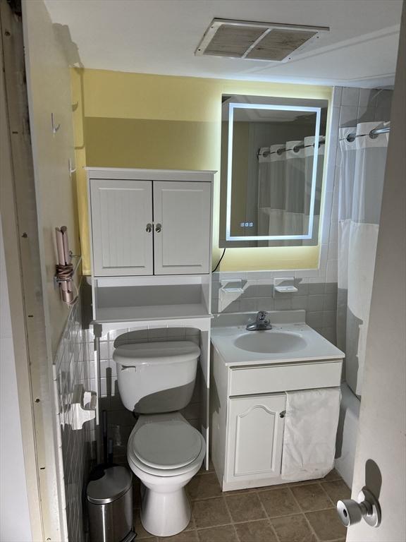 1025 Hancock St Unit 1K, Quincy, MA 02169 - bathroom with toilet, vanity, tile walls, tile patterned flooring, and a shower with curtain