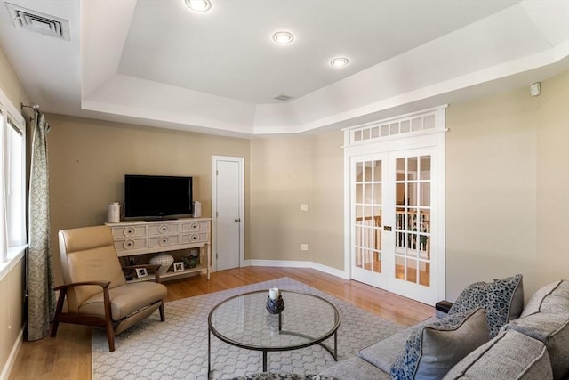 living room with french doors, hardwood / wood-style floors, and a tray ceiling