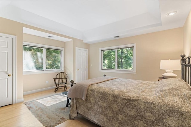 bedroom featuring a tray ceiling and light hardwood / wood-style floors