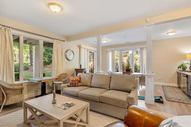 living room with beam ceiling, light hardwood / wood-style flooring, and ornate columns