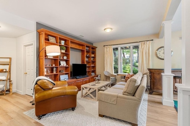 living room with decorative columns and light wood-type flooring