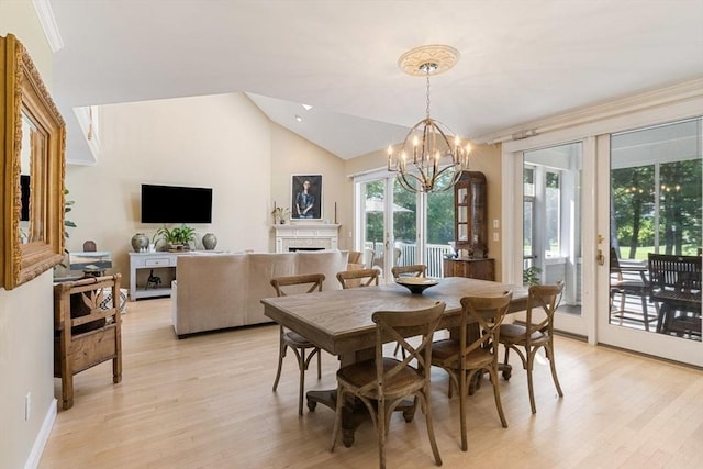 dining space featuring vaulted ceiling, an inviting chandelier, and light hardwood / wood-style flooring