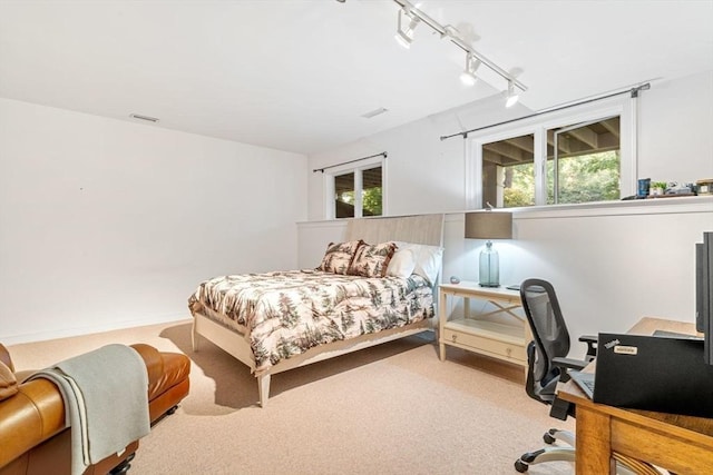 bedroom with track lighting and light carpet