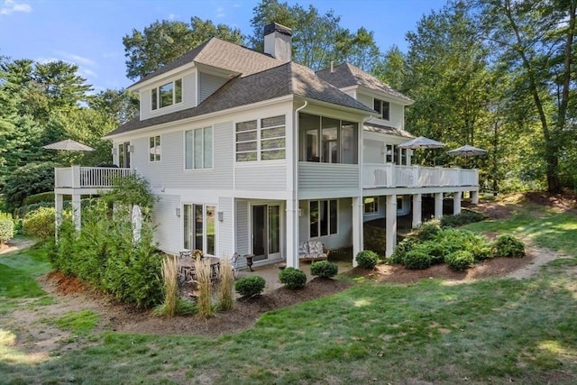 back of property featuring a wooden deck, a lawn, and a sunroom