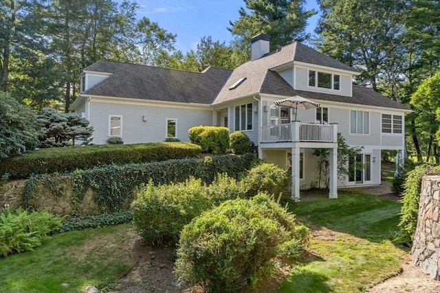 back of property featuring a wooden deck and a lawn