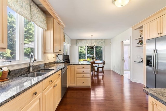 kitchen featuring sink, dark stone countertops, hanging light fixtures, stainless steel appliances, and kitchen peninsula