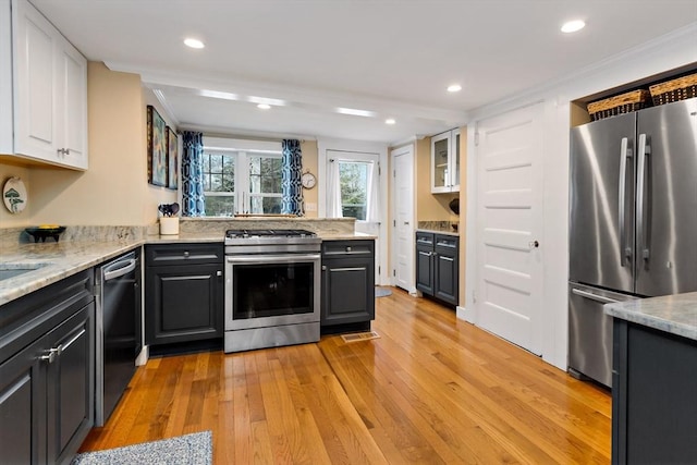 kitchen with white cabinets, light stone counters, kitchen peninsula, stainless steel appliances, and light hardwood / wood-style flooring