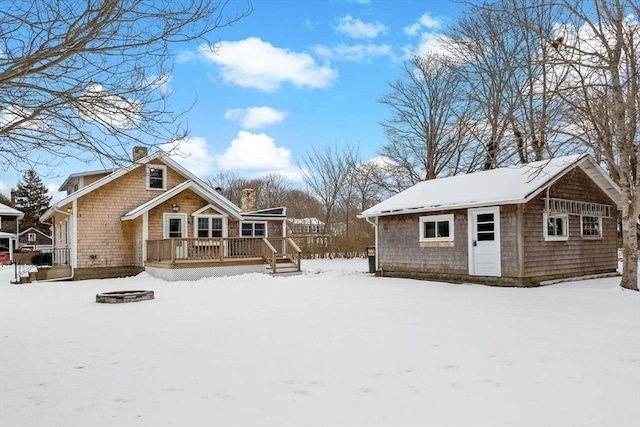 snow covered property featuring an outbuilding, an outdoor fire pit, and a deck