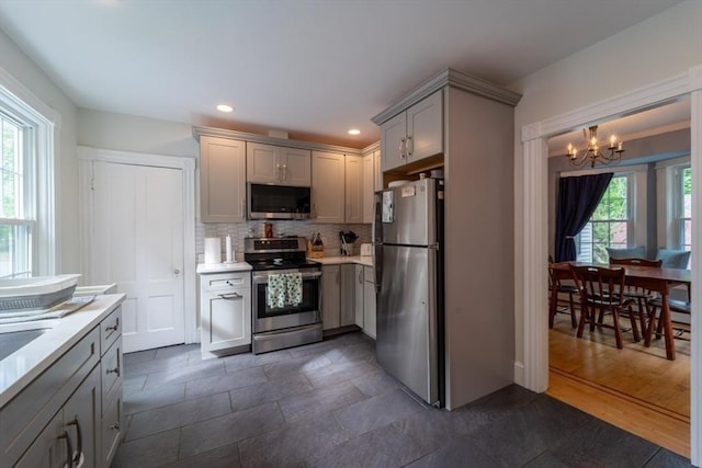 1349 Main St, Holden, MA 01520 - kitchen with stainless steel appliances, a chandelier, light countertops, backsplash, and gray cabinetry