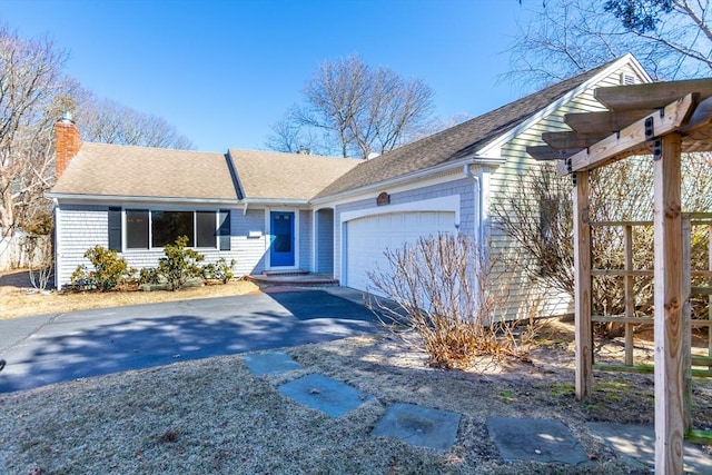 single story home featuring a shingled roof, aphalt driveway, an attached garage, and a chimney