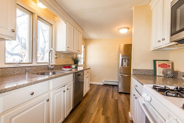 kitchen with a sink, light stone counters, dark wood finished floors, stainless steel appliances, and baseboard heating