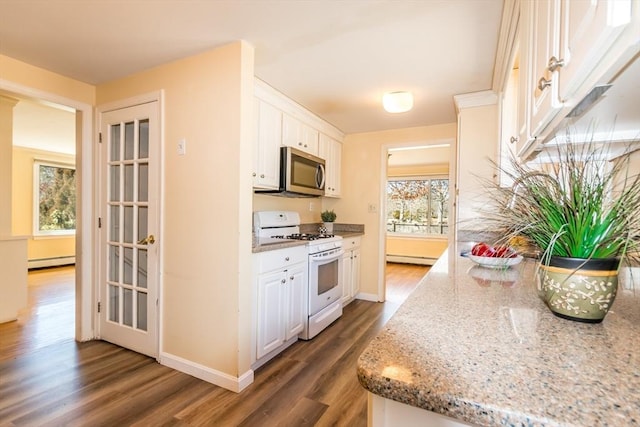 kitchen with wood finished floors, a baseboard radiator, white range with gas cooktop, white cabinets, and stainless steel microwave