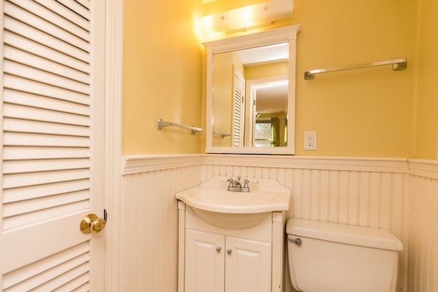 bathroom featuring vanity, toilet, and wainscoting