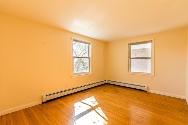 empty room with a baseboard radiator, baseboards, and light wood-style flooring