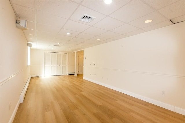 spare room featuring visible vents, light wood-type flooring, baseboards, and a baseboard radiator