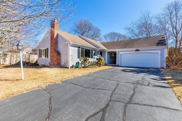 ranch-style home with aphalt driveway, a chimney, a garage, and fence