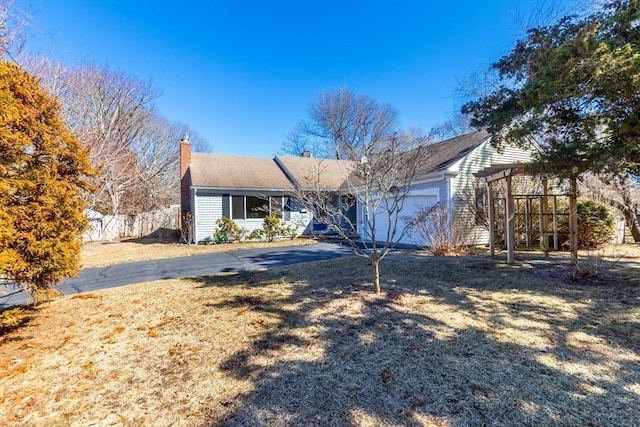 view of front of property featuring fence, a garage, driveway, and a chimney