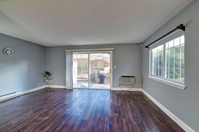 empty room with dark hardwood / wood-style flooring, a healthy amount of sunlight, and a wall mounted air conditioner