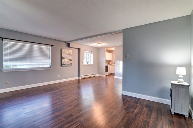 unfurnished living room featuring dark hardwood / wood-style floors, a textured ceiling, and a baseboard heating unit