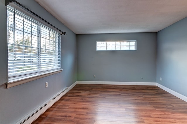 empty room with dark hardwood / wood-style flooring and baseboard heating