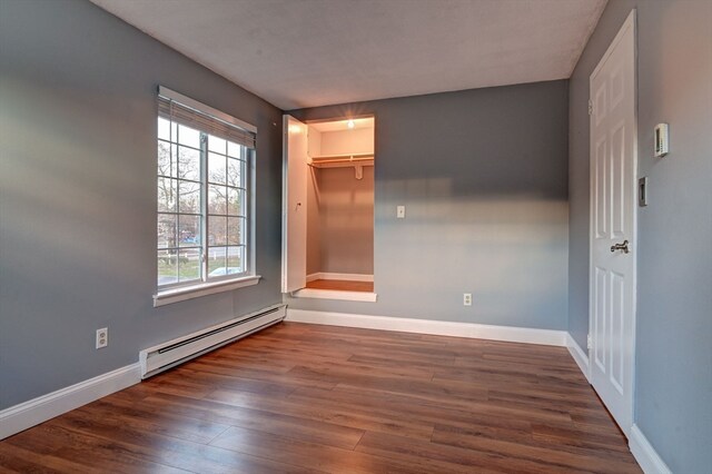 unfurnished room with a baseboard radiator and dark hardwood / wood-style flooring