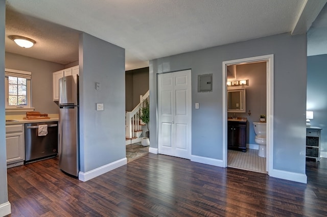 interior space with white cabinetry, stainless steel appliances, a textured ceiling, and dark hardwood / wood-style floors