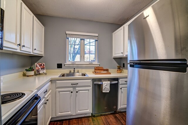 kitchen with stainless steel appliances, white cabinetry, dark wood-type flooring, and a textured ceiling