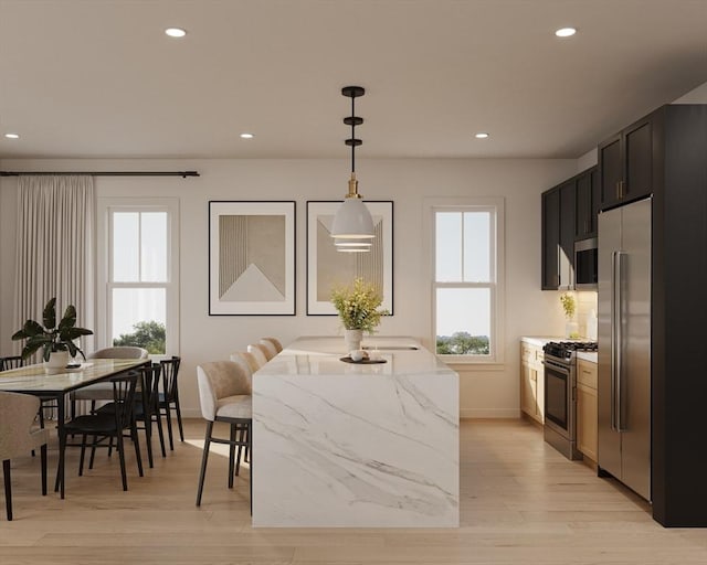 kitchen with light stone countertops, appliances with stainless steel finishes, decorative light fixtures, and light hardwood / wood-style flooring