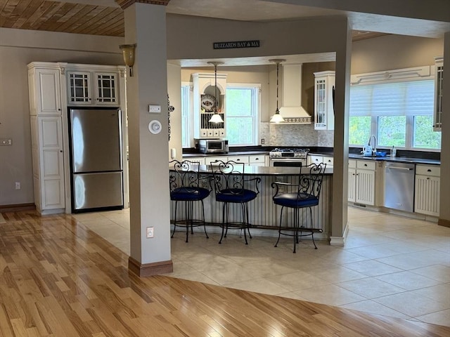3 Wolf Rd, Bourne, MA 02532 - kitchen featuring appliances with stainless steel finishes, premium range hood, dark countertops, a sink, and a kitchen bar
