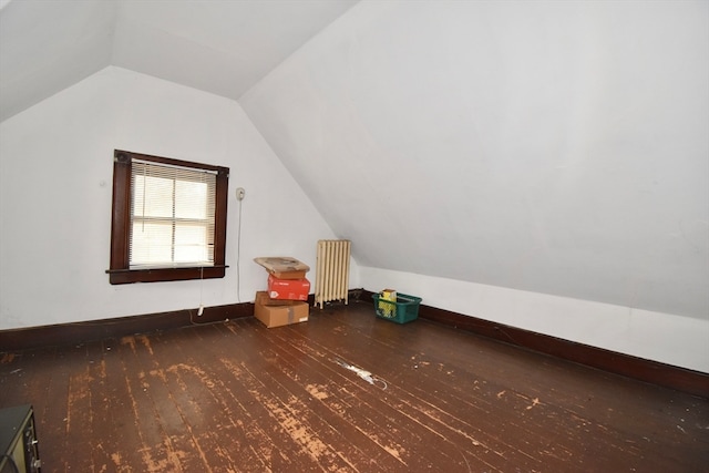 additional living space with dark wood-type flooring, vaulted ceiling, and radiator heating unit