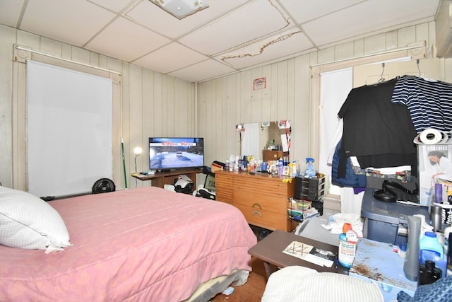 bedroom featuring a drop ceiling and wooden walls