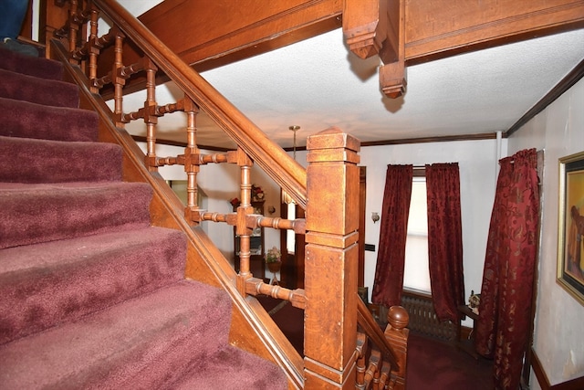 stairway with crown molding and a textured ceiling