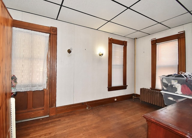 office space with dark wood-type flooring, radiator heating unit, and a drop ceiling