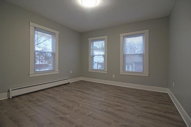empty room featuring a wealth of natural light, a baseboard radiator, baseboards, and dark wood finished floors