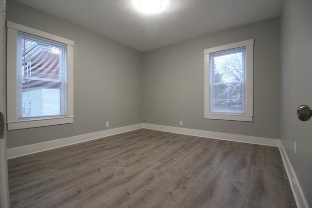 empty room with dark wood-style flooring and baseboards